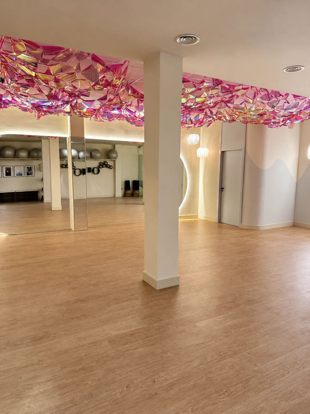 Sala de suelo de Origen, con espejos, material de Pilates y un techo decorativo de colores